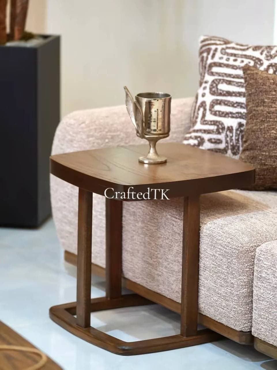 Walnut C-shaped side table beside a cream sofa